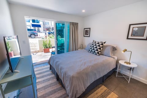 Lower level bedroom provides Queen bed, linens, Roku TV, closet, sliding glass door out to front sub-street patio and seating.