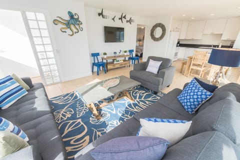 Drop your bags and enjoy a carefree, car-free vacation in this bright and cheery upstairs beach house, just one home from the sand!