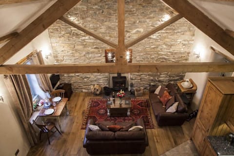 Open plan living room / kitchen with exposed beams and stonework