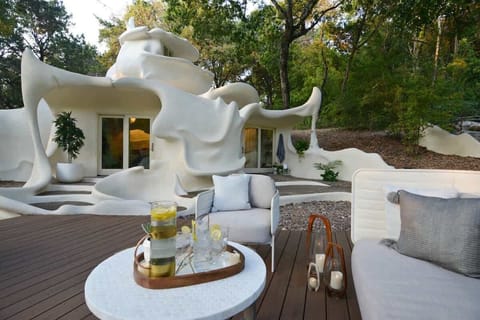 Seamless indoor-outdoor living with a private deck, lounge seating, and sculptural architecture all around.