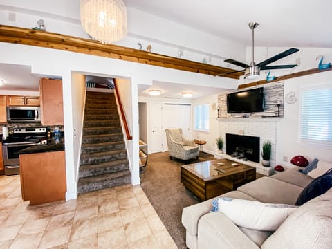 Open plan living area with mounted tv & electric gas fireplace.