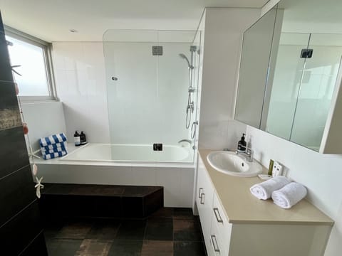 Main bathroom with tub and beach towels 
