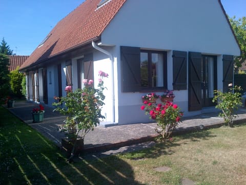 Front of house with south-facing patio and small grass lawn to  hedge