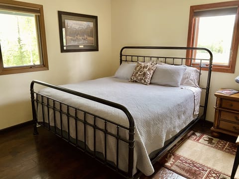 Featured: Upstairs bedroom with a king bed and view of the forest and driveway.