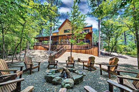 The fire pit in the back yard surrounded by Adirondack chairs.