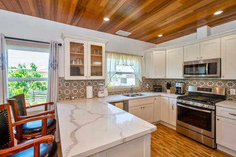 Kitchen with quartz countertop, dishwasher, gas stove and red cedar ceiling