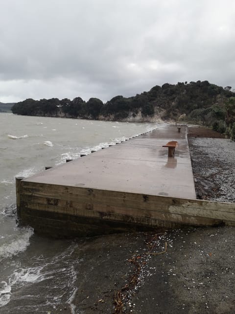 Concrete at beachfront with seating. Wild day at full tide.