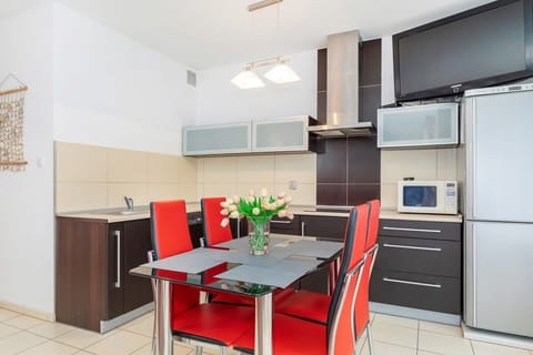 A view of the kitchen with black and wooden cabinets. The area includes a refrigerator, stove, and ample counter space.