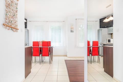 Another angle of the living room showing the red sofa and dining area with a clear view of the kitchen. The space is open and inviting.