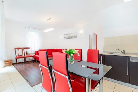 A spacious living room that combines a bright seating area with a red sofa and a dining table with chairs. The open layout allows for easy flow between the living and dining spaces, ideal for hosting guests.