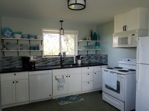 Full kitchen has a dishwasher, oven, fridge, microwave, coffee maker, toaster