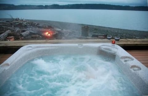 The hot tub sits on the deck just steps from the water!