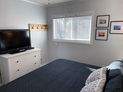 Second bedroom with dresser and large TV.