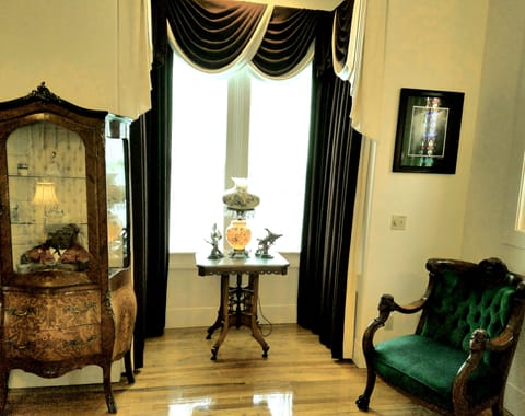 Living room window with antiques, green velvet armchair