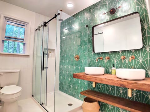 Oversized frameless glass shower with custom double vessel sinks.