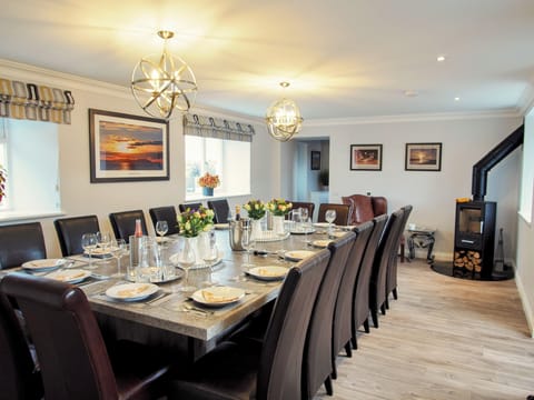 Polished concrete dining table for 16 with leather dining chairs & wood burner.