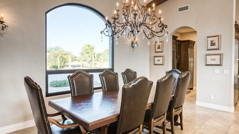 Elegant formal dining room with wooden table, leather chairs, and chandelier.