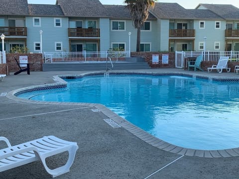 Unit 130 is in right lower background, steps away from the pool and BBQ grill.