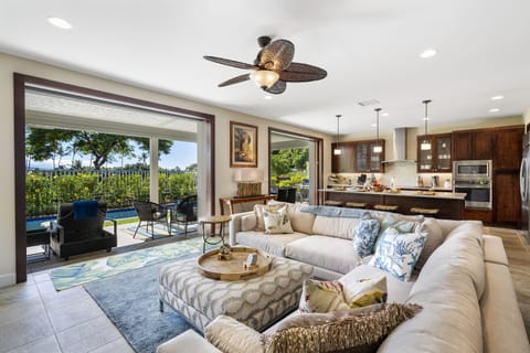 The spacious great room of this Kona Hawai'i vacation rental with a large sectional couch and doors to the back lanai open.