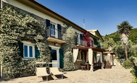 Front of house with glorious jasmine blossom, big shade pergola, table & chairs.