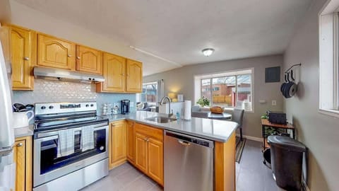Bright and inviting kitchen with wooden cabinetry, stainless steel appliances, and a modern backsplash, seamlessly flowing into the dining area.