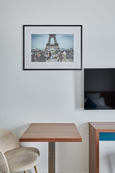 An artful display of the Eiffel Tower photograph adds a touch of Parisian charm to the room, adjacent to the sleek TV setup.