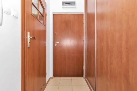 A hallway with wooden doors and built-in closets provides a practical entry space. The sleek design and neutral tones make it a functional yet attractive area.
