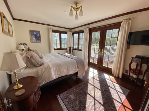 Bedroom with morning sun and french doors that open to wraparound deck