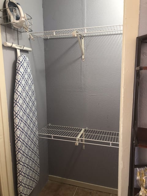 Closet for clothes, ironing board, and iron. 