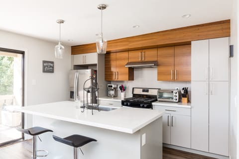Fully equipped modern kitchen featuring stainless steel appliances and stocked with cooking essentials.