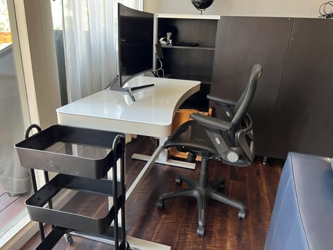 Office space with adjustable desk, monitor and ergonomic office chair.