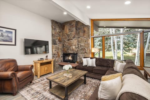 Floor to ceiling windows fill the living area with bright natural light and a serene wooded view.