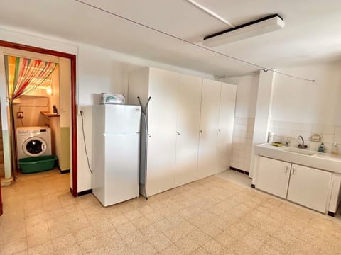 Buanderie, machine à laver, table et fer à repasser et deuxième réfrigérateur.