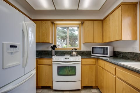 The bright kitchen is surrounded by trees.