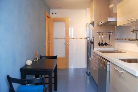 Modern, compact kitchen characterized by light wood fronts and high-quality stainless steel appliances. Efficient design that maximizes functionality and vertical storage.