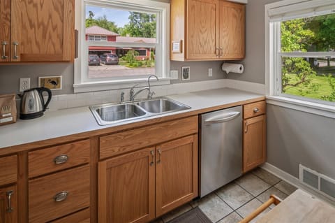 Bright kitchen featuring a large window over the sink, compact fridge, water heater, and classic wooden cupboards with thoughtful touches.