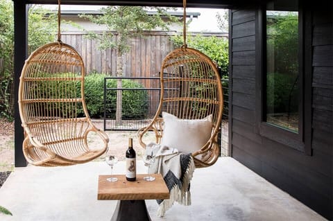 The front porch features four rattan hanging chairs.