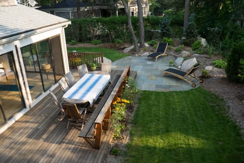Peaceful back yard with deck, large table, and patio. 