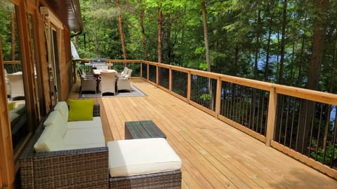 Beautiful 48x12ft deck with plush sofa as well as wooden table, chairs, and BBQ
