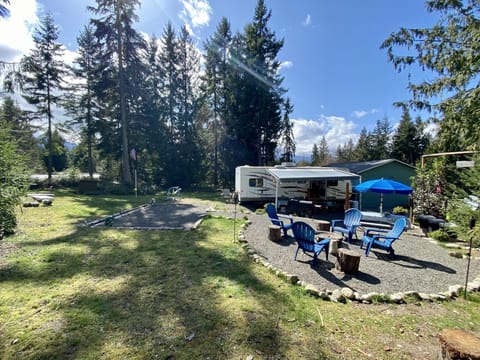 RV with BBQ, picnic table, fire pit, tent pad and grass area with outdoor games