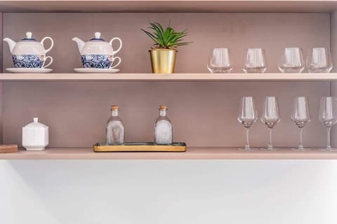 A close-up of shelving with decorative items, including glassware and potted plants. The shelves are wooden with a sleek, modern finish.