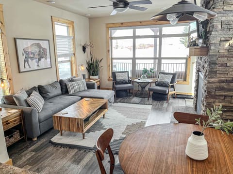 【Living Room】Stone fireplace, leather sectional, and river light through a wall of windows