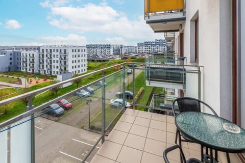 A scenic view of a residential area, captured from a balcony. It showcases modern apartment buildings, green spaces, and parking areas.