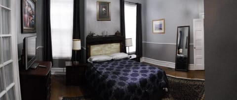 Bedroom with Queen bed, TV, closet with iron and ironing board, pedestal fan