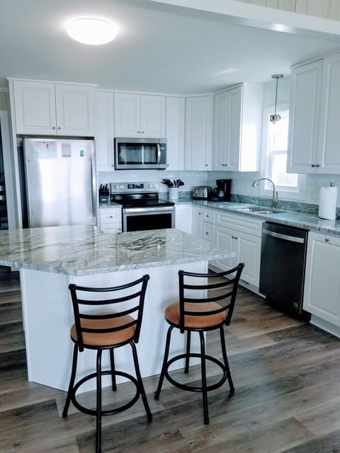 New well-appointed kitchen with granite. Two barstools at the bar.