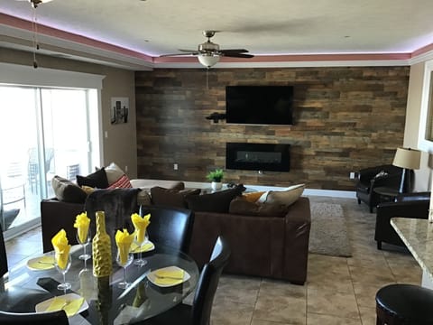 Large open concept living/dining room with wall mounted fireplace and big screen