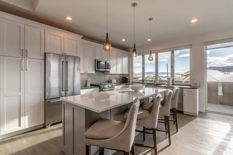 The open kitchen has modern stainless appliances and seating for four at the breakfast bar