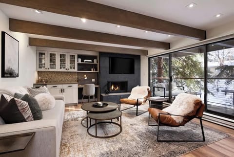 Spacious living room featuring a queen size sleeper sofa, built-in bar/desk area, and smart TV, overlooking the Roaring Fork River