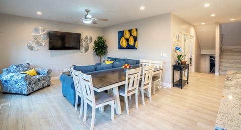 UNIT A (4Bdrm): The living room boasts a captivating blue aesthetic and is outfitted with a Smart TV. Ample seating arrangements invite family and friends to gather around the television, while the open layout seamlessly connects to the kitchen, ensuring everyone can enjoy each other's company.

Dining table for 6 guests, plus bar stools at the nearby kitchen island.