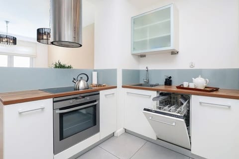 A modern kitchen with sleek white cabinets, wooden countertops, and a minimalist design.